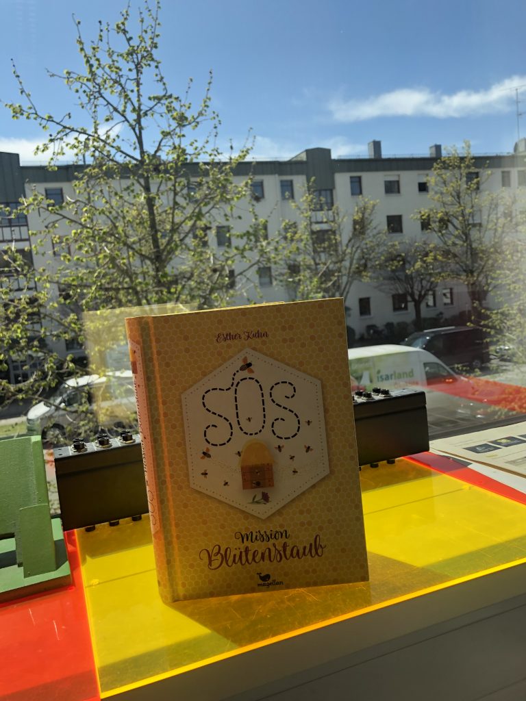 Das Buch "SOS Mission Blütenstaub" - Es ist im Honigwaben-Look gestaltet mit vielen Bienen - steht auf einem Fensterbrett im Südpol-Studio
