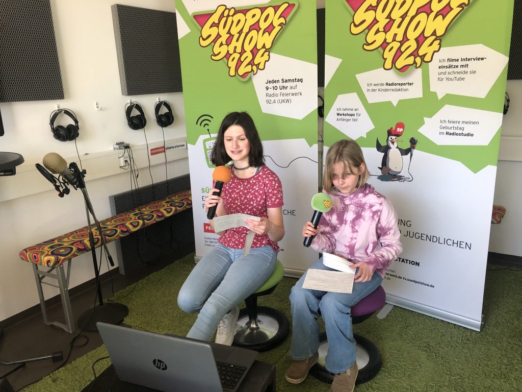 Das war unser Interview- Set-Up: Die Reporterinnen sitzen vor einem Computer mit Funkmikrofonen in der Hand