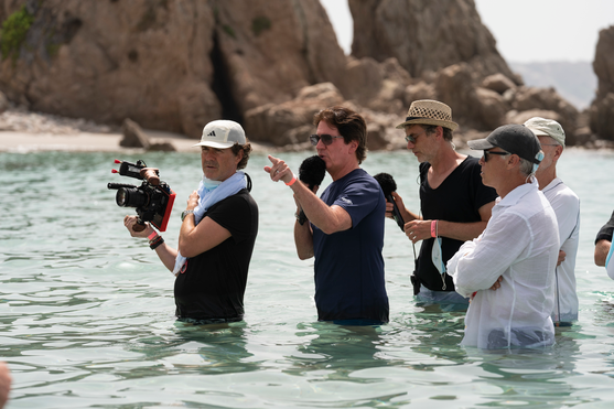 Rob Marshall sagt bei den Dreharbeiten etwas durch ein Mikrofon. Er steht hinter dem Kameramann und das ganze Team ist bis zur Hüfte im Wasser.